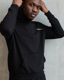 IMUSKOP Under The El Hoodie in black, worn, front with small IMUSKOP chest print